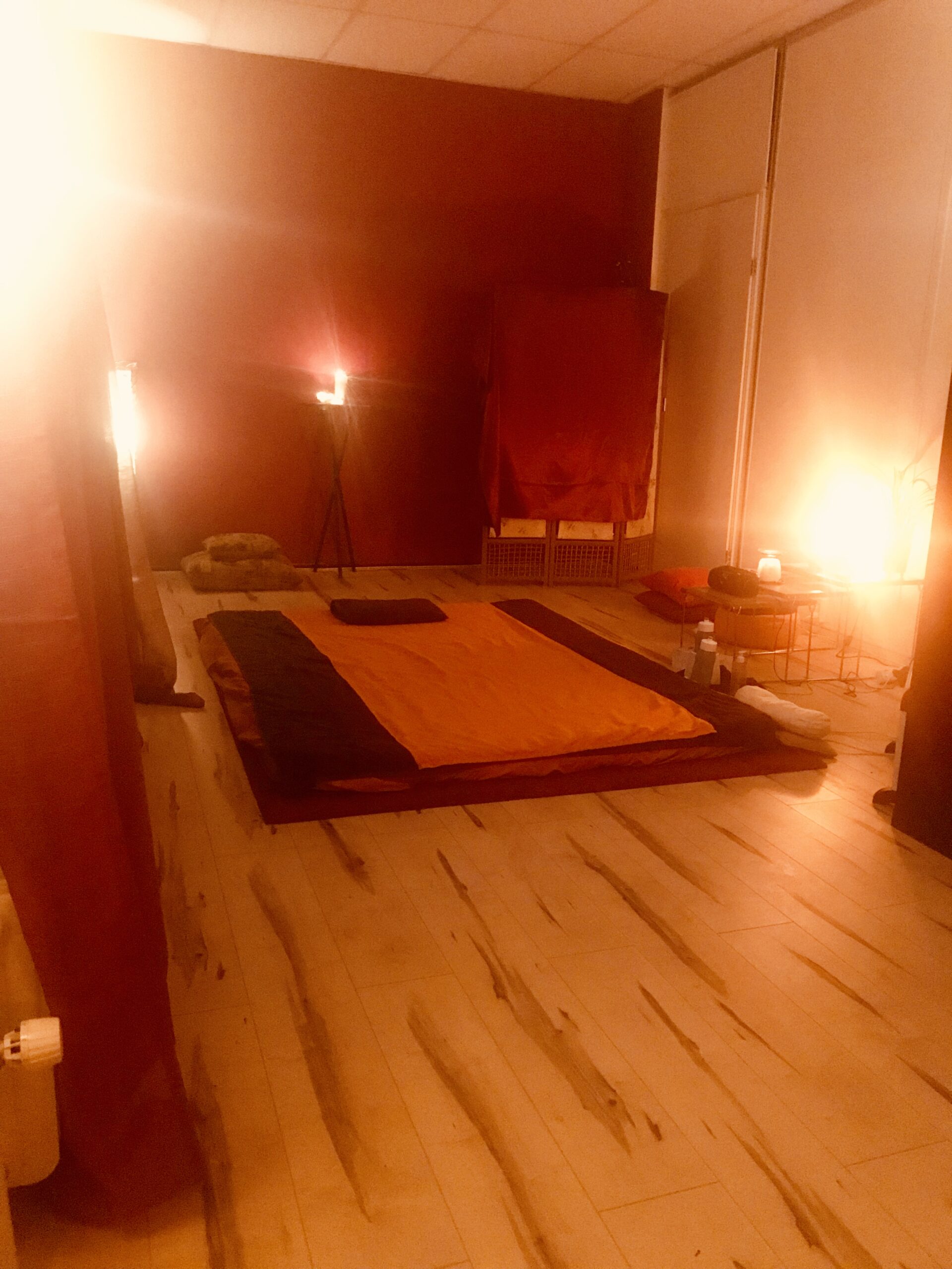 Een kamer met een matras op de grond en kaarslicht